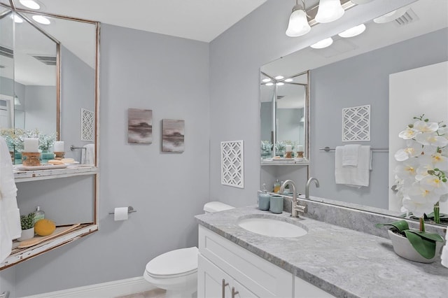 bathroom with vanity, toilet, baseboards, and visible vents