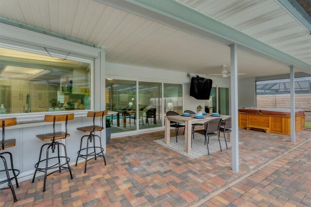 view of patio / terrace featuring ceiling fan, a hot tub, and an outdoor bar