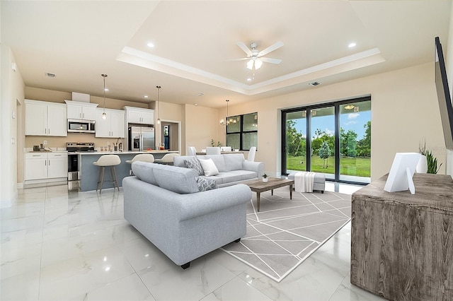 living room featuring a tray ceiling, ornamental molding, and ceiling fan