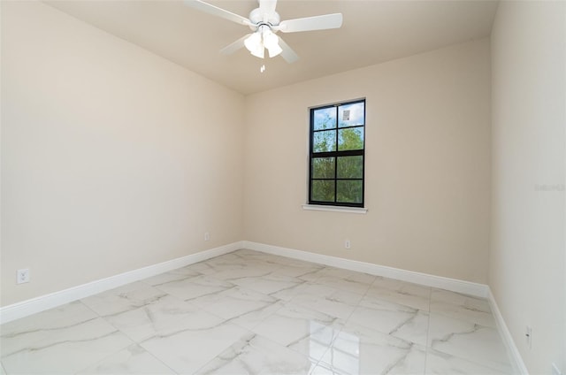 empty room featuring marble finish floor, a ceiling fan, and baseboards