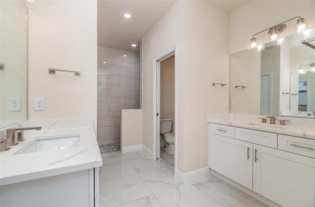 full bath featuring marble finish floor, two vanities, a sink, and toilet