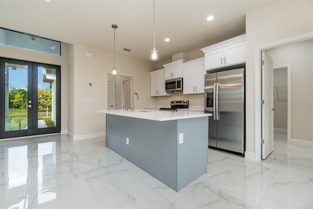 kitchen with white cabinets, marble finish floor, appliances with stainless steel finishes, a center island with sink, and pendant lighting