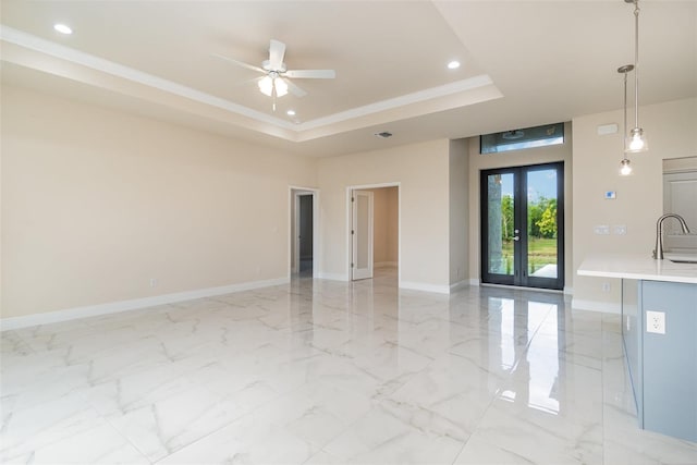 spare room with french doors, sink, ornamental molding, a raised ceiling, and ceiling fan