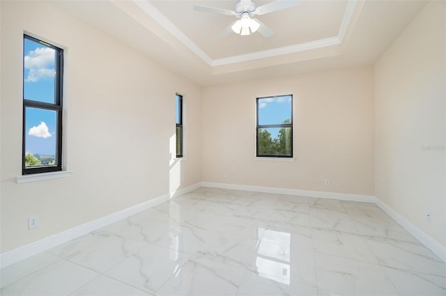 empty room featuring marble finish floor, a raised ceiling, and baseboards