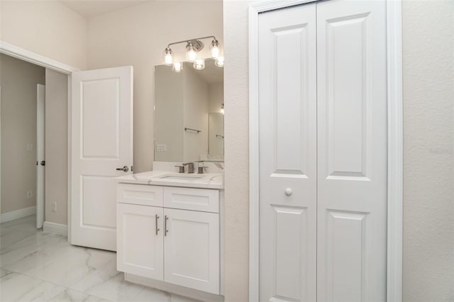 bathroom featuring marble finish floor, baseboards, a closet, and vanity