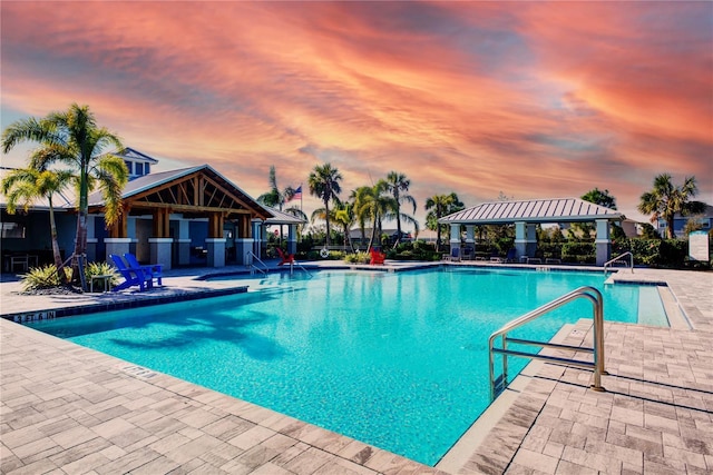 pool at dusk featuring a gazebo and a patio