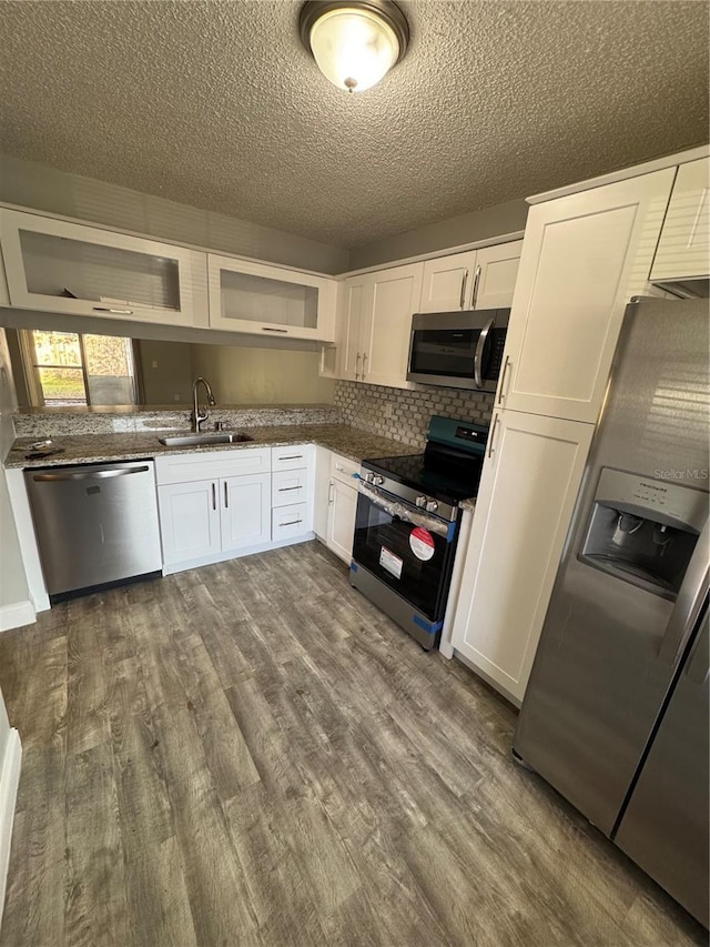 kitchen with dark wood-type flooring, sink, a textured ceiling, appliances with stainless steel finishes, and white cabinetry