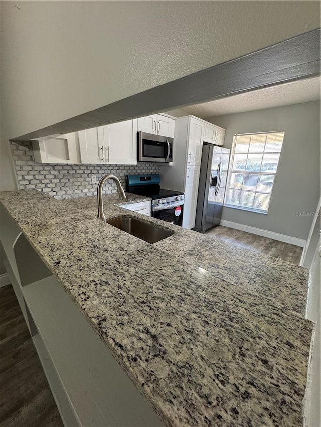 kitchen featuring white cabinets, sink, decorative backsplash, light stone counters, and stainless steel appliances