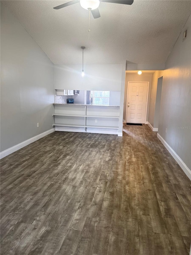 unfurnished living room with ceiling fan, dark hardwood / wood-style floors, and a textured ceiling