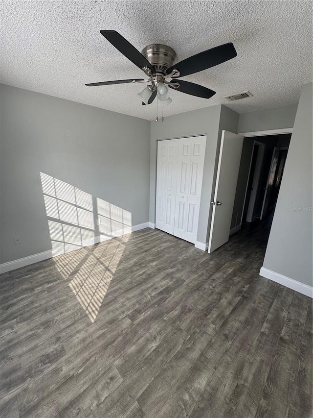 unfurnished bedroom with a textured ceiling, a closet, ceiling fan, and dark hardwood / wood-style floors