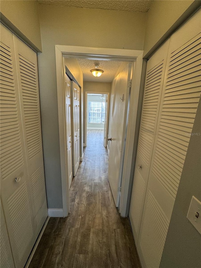 hallway with dark hardwood / wood-style floors and a textured ceiling