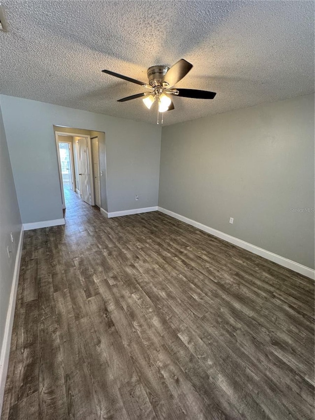 empty room with ceiling fan, dark hardwood / wood-style floors, and a textured ceiling