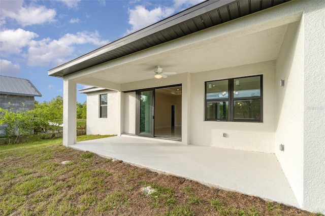 rear view of property featuring a patio area, a lawn, a ceiling fan, and stucco siding