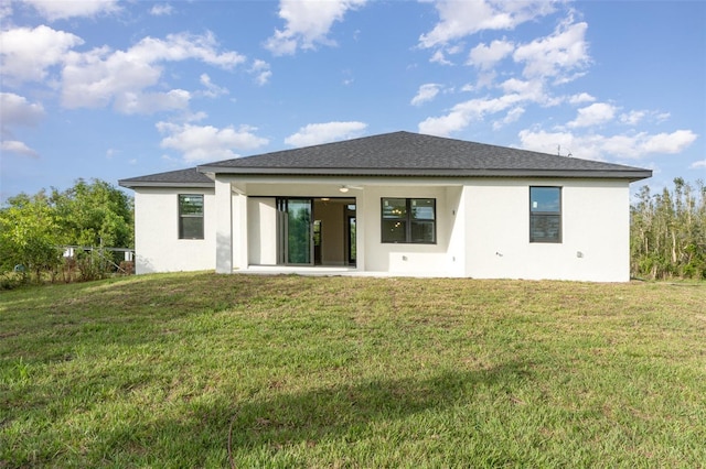 rear view of house with a patio area, a lawn, and stucco siding