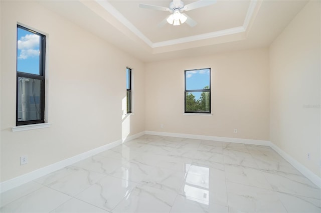 empty room with crown molding, a tray ceiling, and ceiling fan