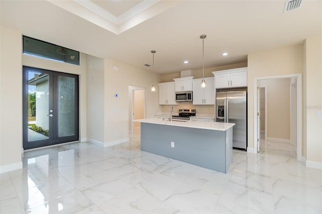 kitchen featuring french doors, a center island with sink, hanging light fixtures, appliances with stainless steel finishes, and white cabinets