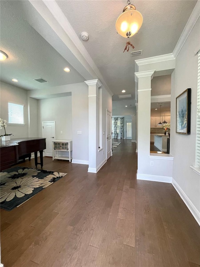 hallway featuring crown molding, dark hardwood / wood-style floors, decorative columns, and a textured ceiling