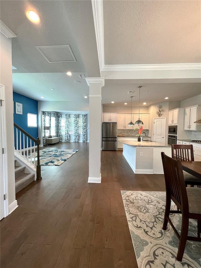 dining room with ornate columns, sink, a textured ceiling, and dark hardwood / wood-style floors