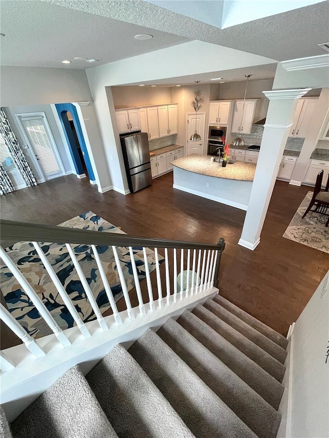 stairway with sink, hardwood / wood-style flooring, and a textured ceiling