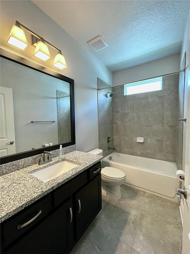 full bathroom featuring vanity, tiled shower / bath combo, a textured ceiling, and toilet