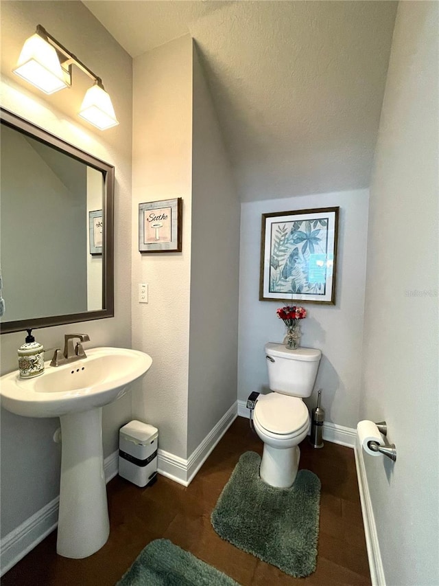 bathroom featuring hardwood / wood-style flooring, vaulted ceiling, sink, and toilet