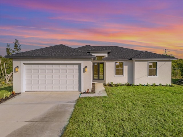 prairie-style home with a garage and a yard