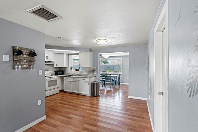 kitchen with tasteful backsplash, white electric range, white cabinets, light hardwood / wood-style flooring, and sink