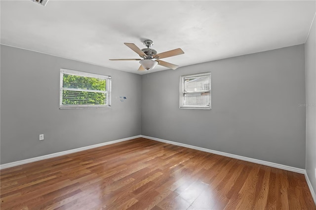 spare room featuring wood-type flooring, a wealth of natural light, and ceiling fan