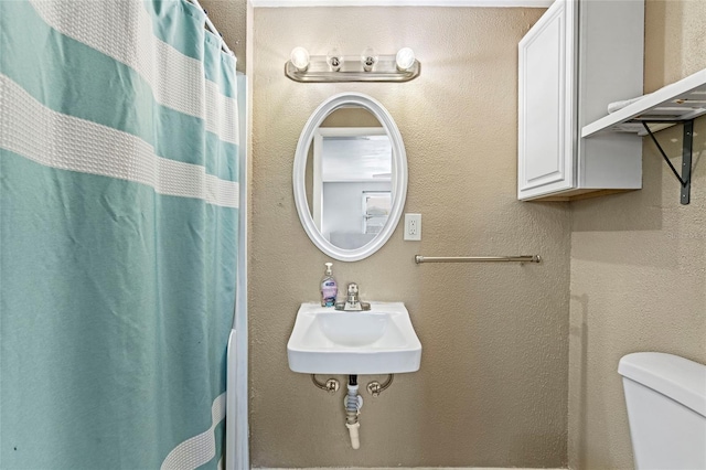 bathroom featuring toilet, sink, and a shower with shower curtain