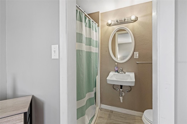 bathroom with toilet, a shower with shower curtain, and sink