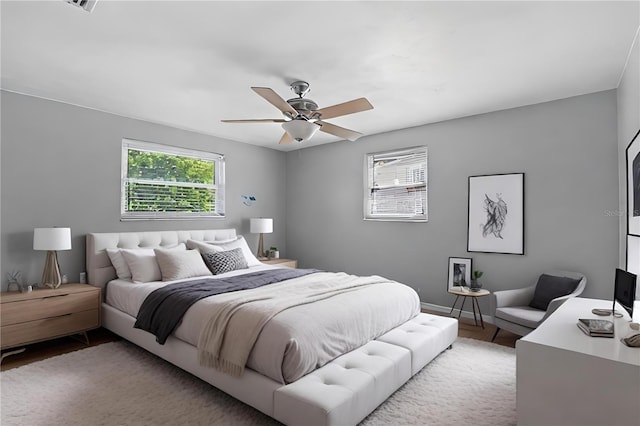 bedroom with ceiling fan, hardwood / wood-style floors, and multiple windows