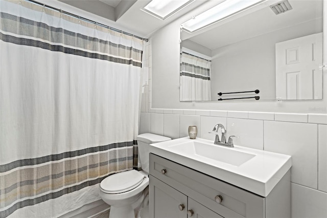 bathroom with toilet, tile walls, and vanity