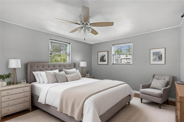 bedroom featuring ceiling fan, light hardwood / wood-style floors, and multiple windows