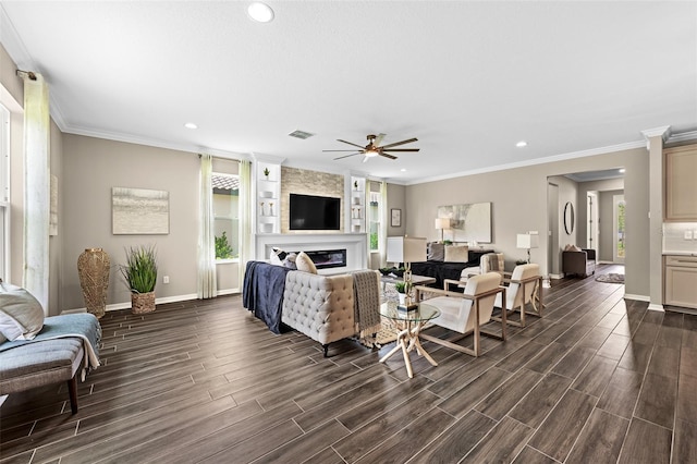 living room with ceiling fan, ornamental molding, a large fireplace, and built in shelves