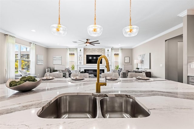 kitchen featuring pendant lighting, sink, a large fireplace, and light stone counters