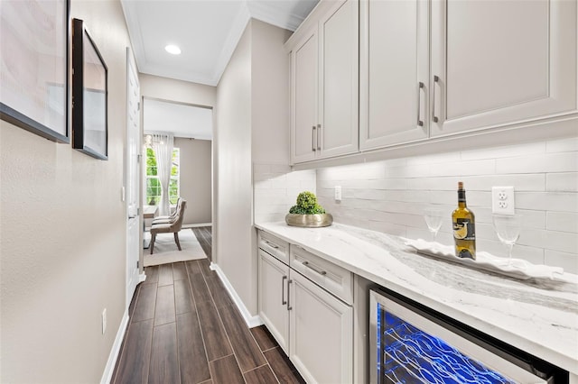 bar featuring tasteful backsplash, crown molding, white cabinetry, beverage cooler, and light stone counters