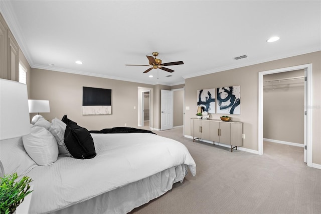 bedroom with ceiling fan, crown molding, light carpet, a walk in closet, and a closet