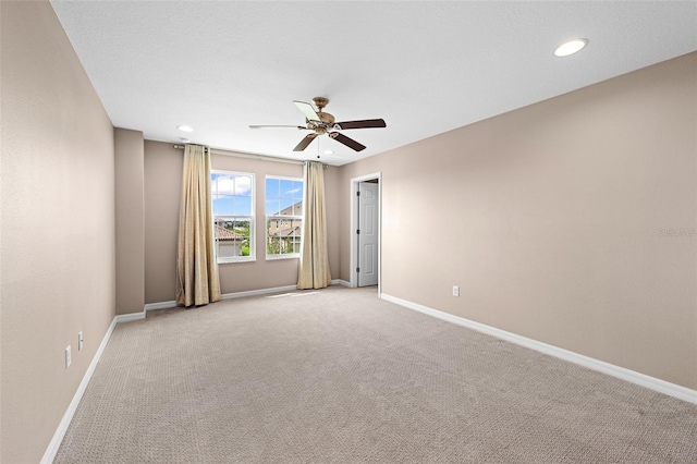 spare room featuring ceiling fan and light carpet