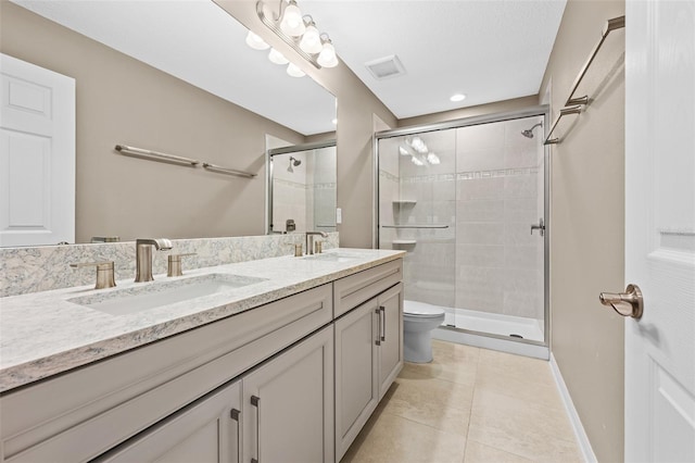 bathroom with a shower with shower door, vanity, tile patterned floors, and toilet