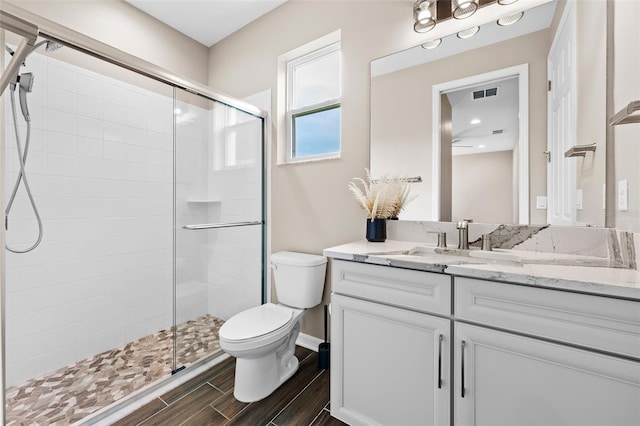 bathroom featuring toilet, a shower with shower door, and vanity