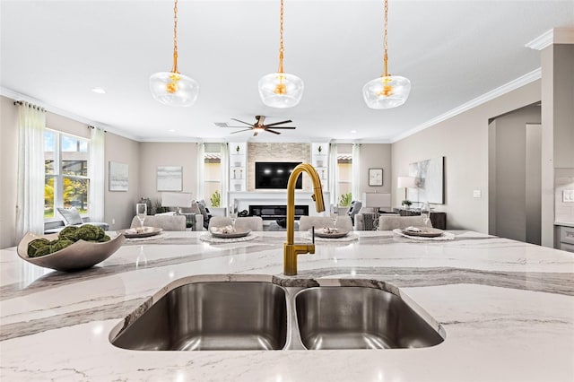 kitchen featuring a large fireplace, a sink, crown molding, and open floor plan
