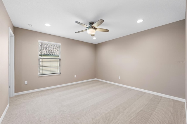 spare room featuring light carpet, baseboards, and ceiling fan