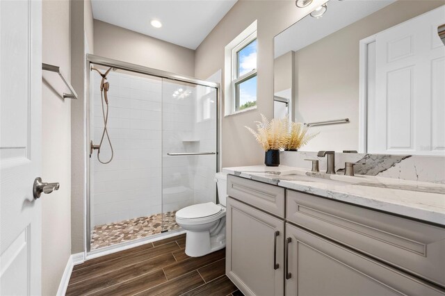 full bath with toilet, vanity, a shower stall, wood finish floors, and recessed lighting