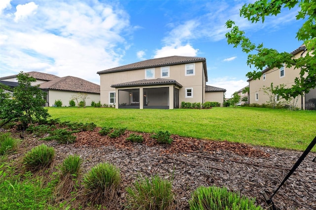 back of house with stucco siding, a tile roof, a sunroom, and a yard