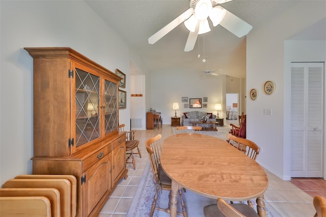 tiled dining room with a textured ceiling, ceiling fan, and vaulted ceiling