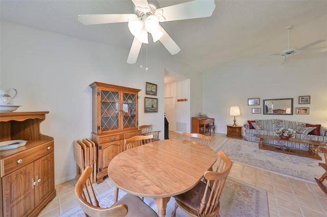 tiled dining room featuring ceiling fan and high vaulted ceiling