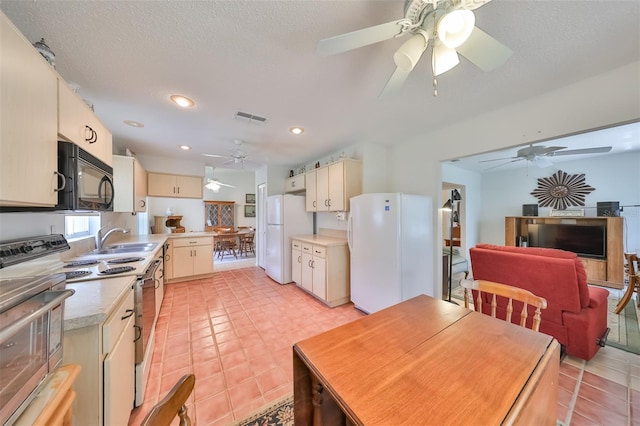 kitchen featuring range with two ovens, white refrigerator, light tile patterned floors, cream cabinetry, and ceiling fan