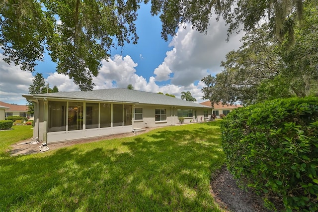 back of property featuring a sunroom and a lawn