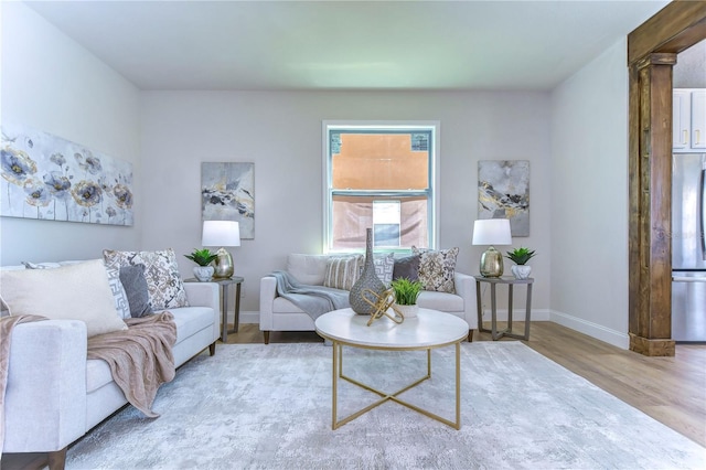 living room with light hardwood / wood-style floors and ornate columns