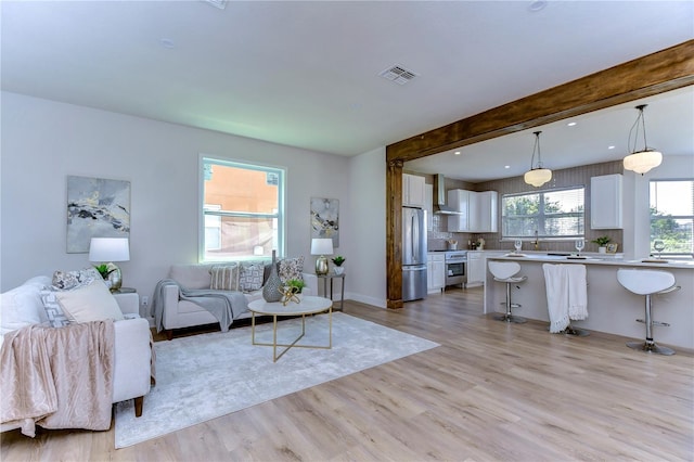 living room featuring beamed ceiling and light hardwood / wood-style floors